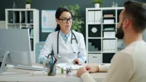 Médica atendiendo a un paciente en la mesa de su consulta