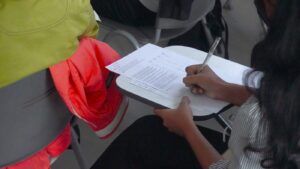 Estudiante escribiendo en un cuaderno durante un examen