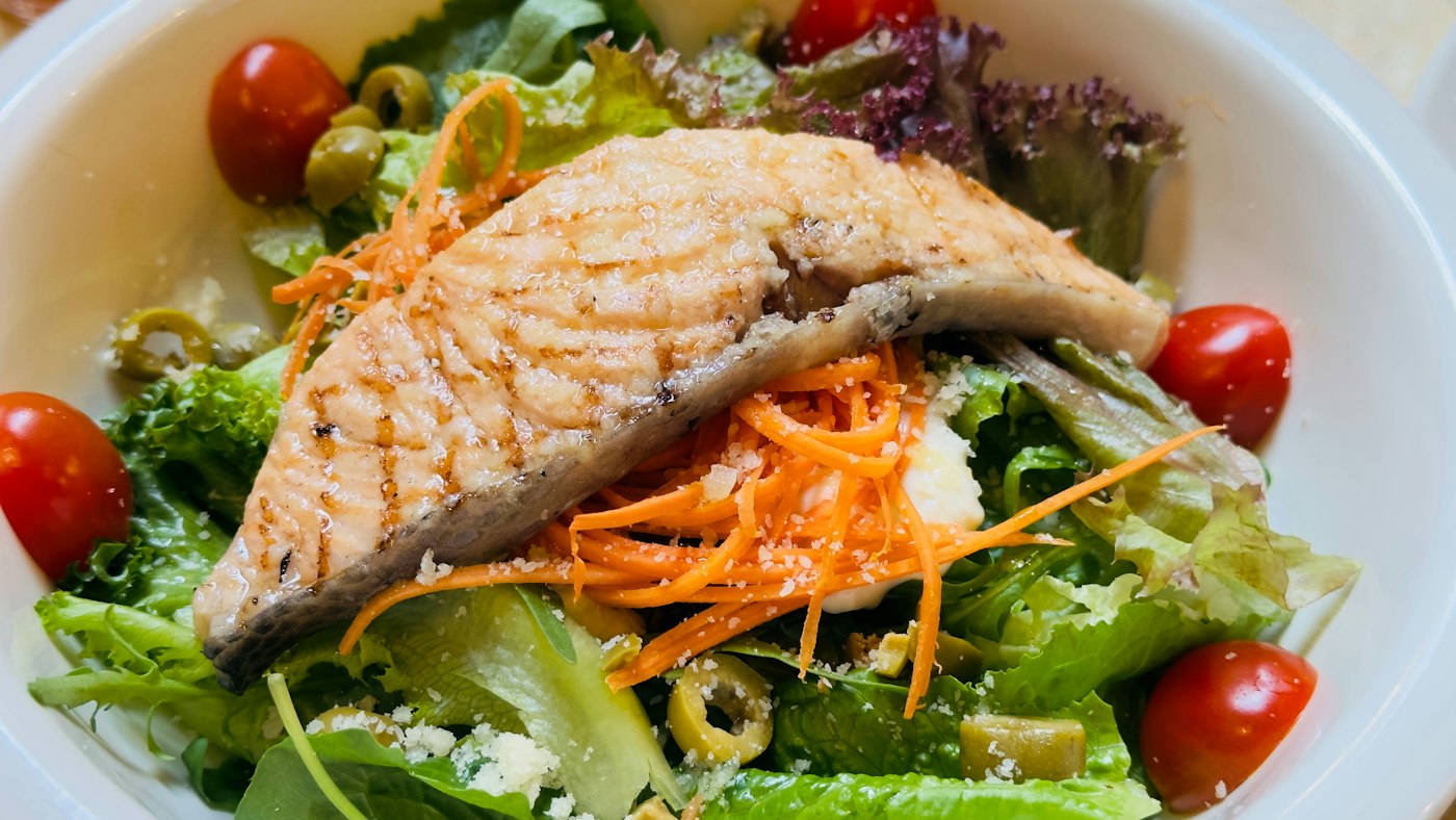 Salmón a la plancha sobre ensalada verde con tomate cherry y zanahoria