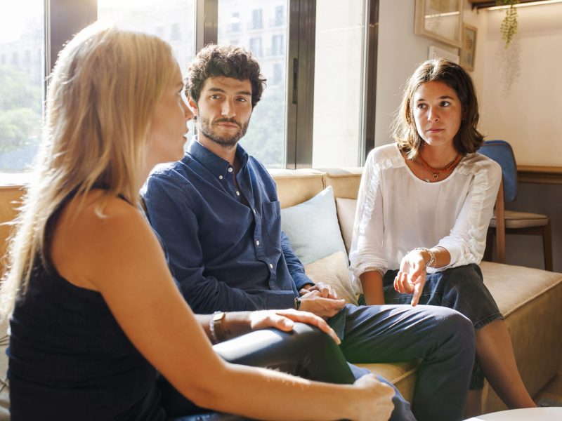 Team of young positive coworkers gathering discussing ideas for startup project while having meeting in creative workspace.